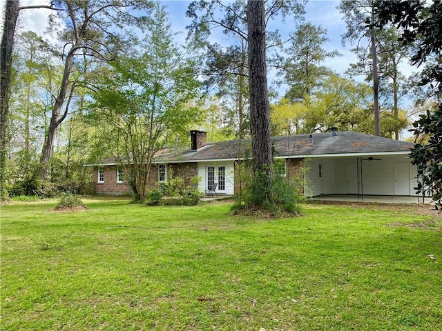 108 N Dr, Covington, LA 70433 - rear view of property with french doors, a yard, a chimney, and an attached carport