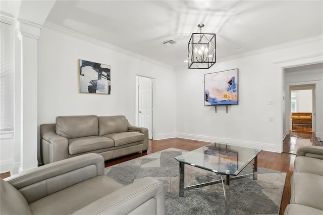 living room with decorative columns, hardwood / wood-style floors, ornamental molding, and a notable chandelier