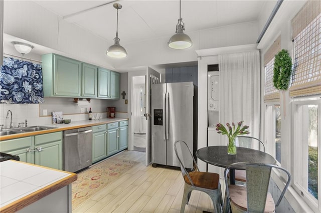 kitchen with decorative light fixtures, stainless steel appliances, plenty of natural light, and light hardwood / wood-style floors