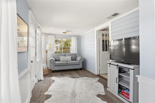 living room with hardwood / wood-style flooring and wood walls