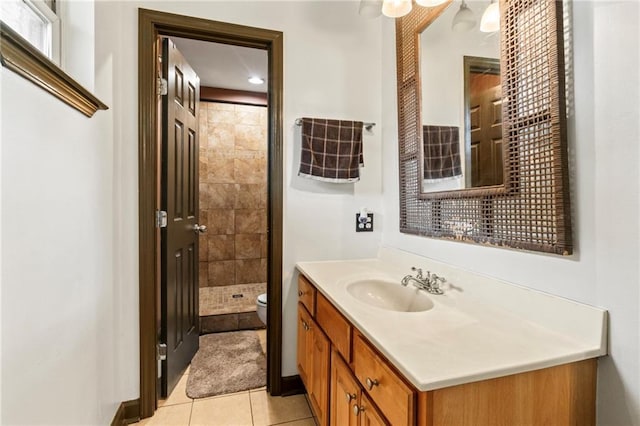 bathroom featuring tile patterned flooring, vanity, toilet, and tiled shower