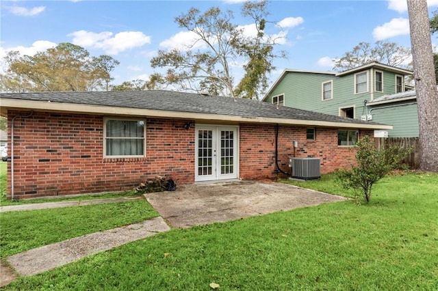 rear view of house with central AC unit, a patio area, a yard, and french doors