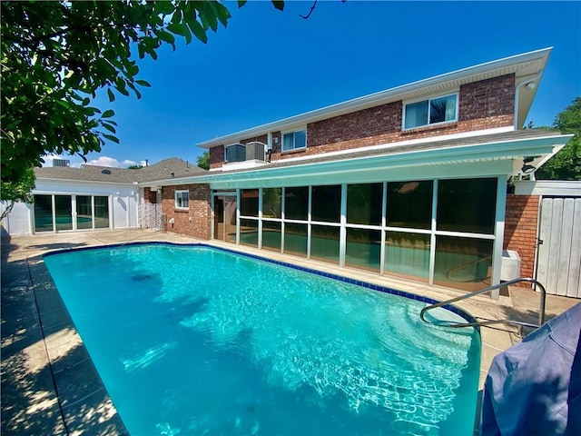 back of house featuring an outdoor pool, brick siding, and a patio area