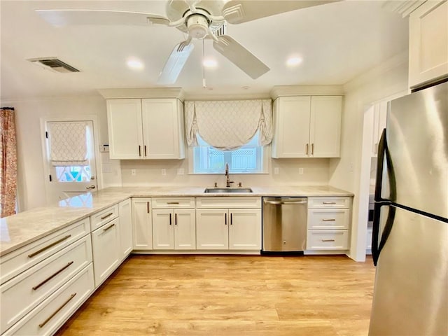 kitchen featuring visible vents, light wood-type flooring, stainless steel appliances, white cabinetry, and a sink