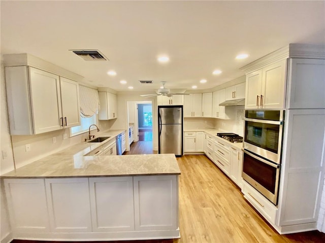 kitchen featuring visible vents, light countertops, a peninsula, stainless steel appliances, and a sink