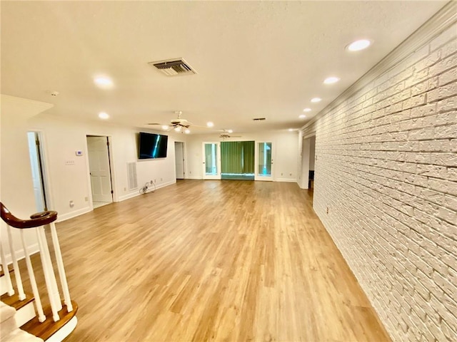 interior space with visible vents, light wood-style flooring, brick wall, and a ceiling fan