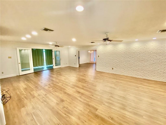 unfurnished room featuring visible vents, light wood-style flooring, brick wall, and ceiling fan