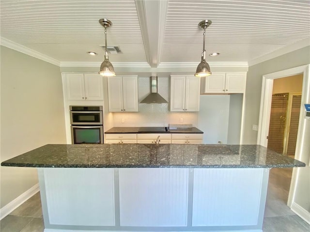 kitchen with stainless steel double oven, white cabinetry, a spacious island, and wall chimney range hood