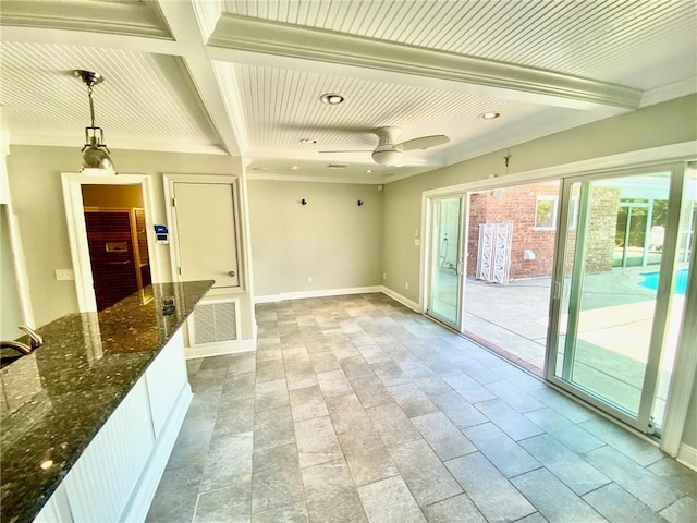 interior space featuring visible vents, ceiling fan, baseboards, dark stone counters, and beam ceiling