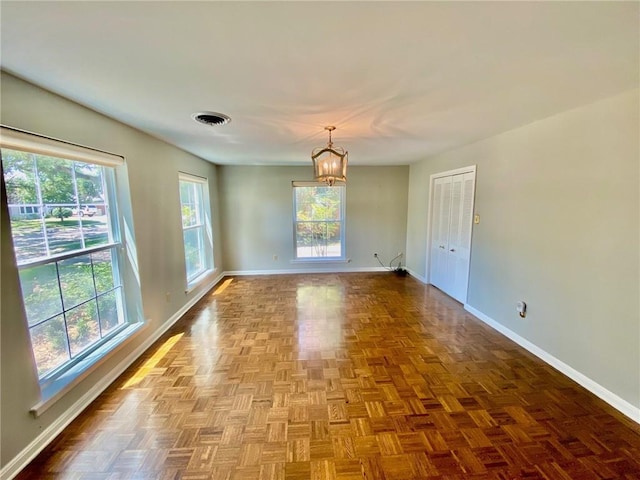 unfurnished room featuring a chandelier, visible vents, and baseboards