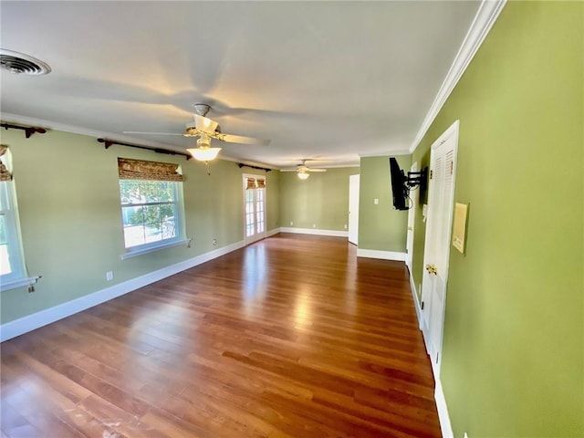 empty room with visible vents, crown molding, baseboards, wood finished floors, and a ceiling fan