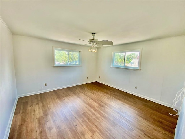 unfurnished room with a healthy amount of sunlight, a ceiling fan, baseboards, and wood finished floors