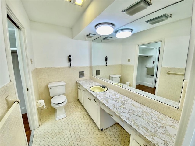 bathroom featuring a wainscoted wall, vanity, toilet, and tile walls