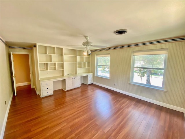 unfurnished bedroom with visible vents, baseboards, wood finished floors, and built in desk