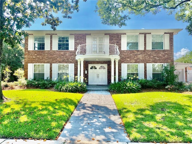 view of front of home featuring brick siding, a balcony, and a front lawn