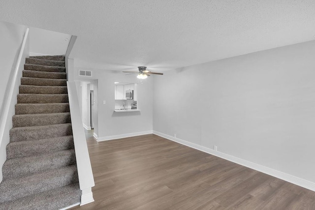 interior space featuring ceiling fan, wood-type flooring, and a textured ceiling