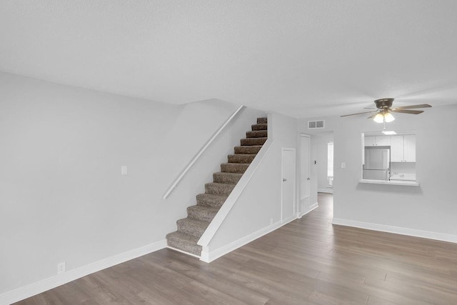 staircase with wood-type flooring and ceiling fan