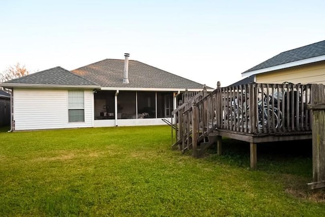 rear view of property with a yard, a deck, and a sunroom