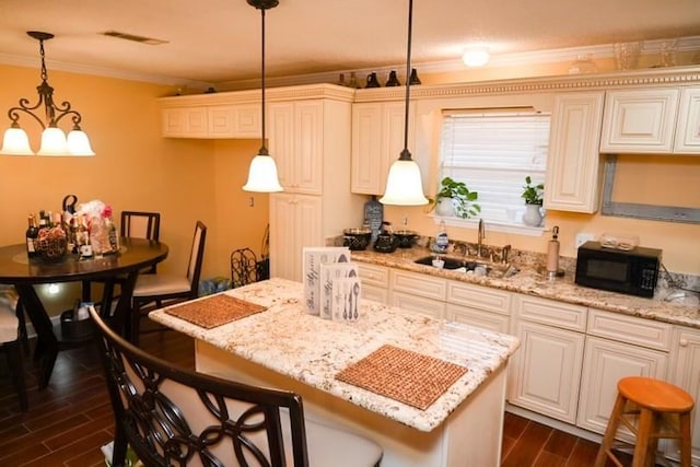 kitchen featuring a kitchen breakfast bar, sink, decorative light fixtures, and dark wood-type flooring