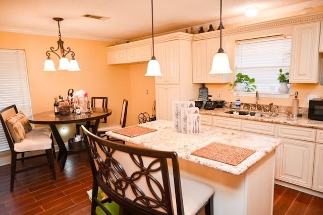 kitchen with dark hardwood / wood-style flooring, sink, a center island, and pendant lighting