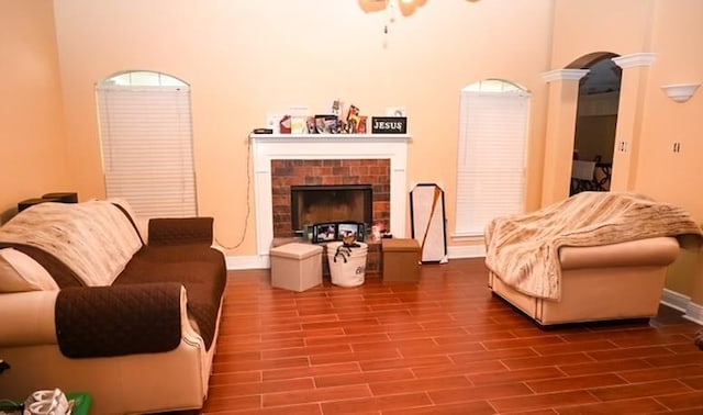 living room featuring decorative columns, a fireplace, a towering ceiling, and wood-type flooring