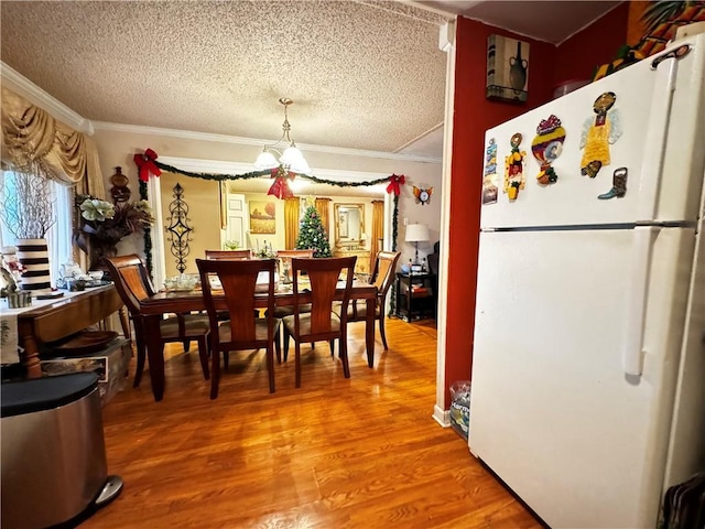 dining room with hardwood / wood-style floors, ornamental molding, and a textured ceiling