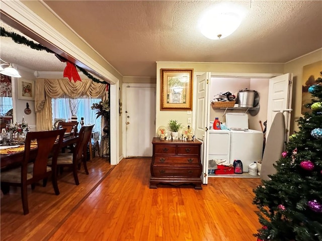 dining space featuring washer and dryer, a textured ceiling, hardwood / wood-style flooring, and crown molding