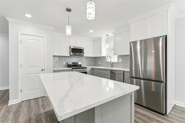 kitchen with white cabinets, appliances with stainless steel finishes, a center island, and hanging light fixtures