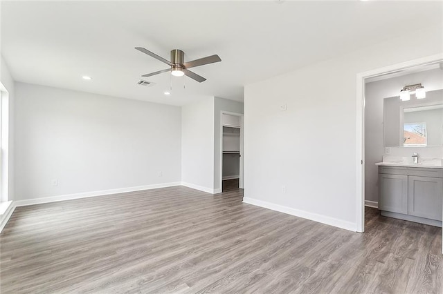 interior space featuring a walk in closet, light wood-type flooring, ensuite bathroom, ceiling fan, and a closet