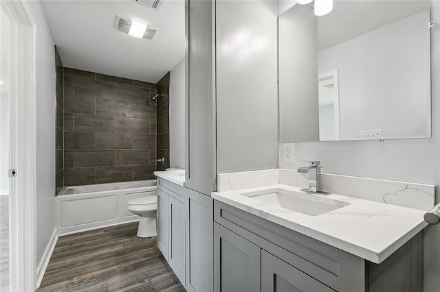 full bathroom with toilet, vanity, wood-type flooring, and tiled shower / bath