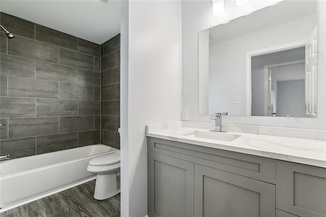 full bathroom with hardwood / wood-style floors, tiled shower / bath combo, toilet, and vanity