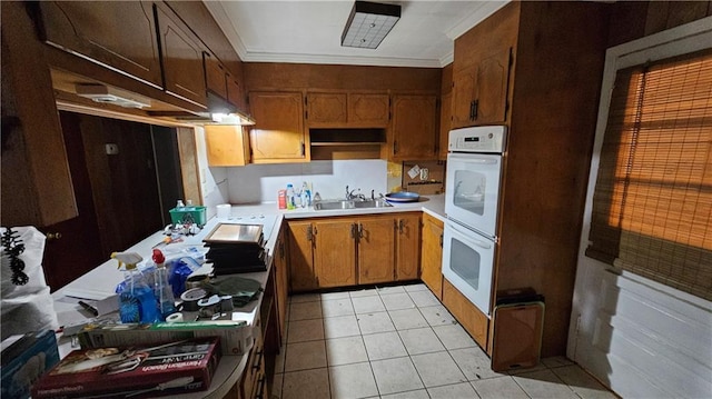 kitchen featuring double oven, sink, light tile patterned flooring, and ornamental molding