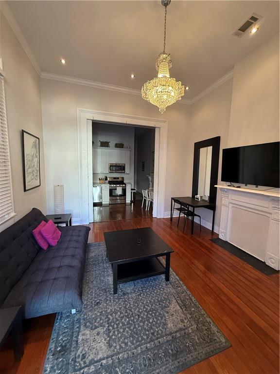 living room featuring dark hardwood / wood-style flooring, an inviting chandelier, and ornamental molding