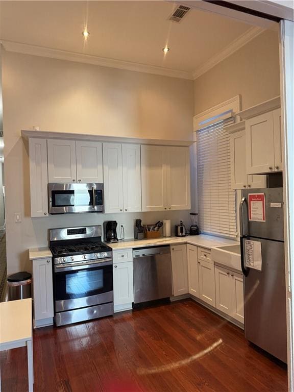 kitchen featuring white cabinets, stainless steel appliances, dark hardwood / wood-style floors, and ornamental molding