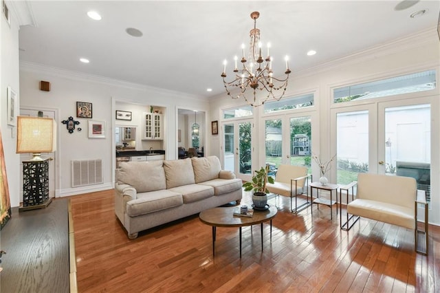 living room featuring hardwood / wood-style floors, french doors, crown molding, and an inviting chandelier