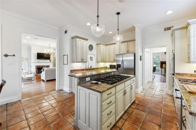 kitchen with a fireplace, dark stone countertops, ornamental molding, and stainless steel appliances