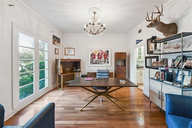 home office featuring hardwood / wood-style floors, an inviting chandelier, ornamental molding, and a healthy amount of sunlight