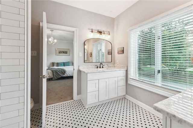 bathroom featuring a notable chandelier, vanity, toilet, and a wealth of natural light