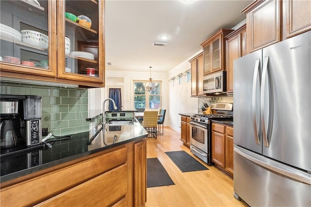 kitchen featuring backsplash, an inviting chandelier, sink, appliances with stainless steel finishes, and decorative light fixtures