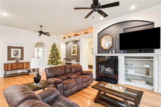 living room with a fireplace, ceiling fan with notable chandelier, light hardwood / wood-style flooring, and lofted ceiling