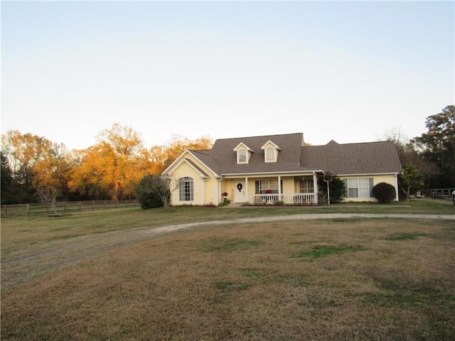 cape cod house featuring a porch and a front lawn