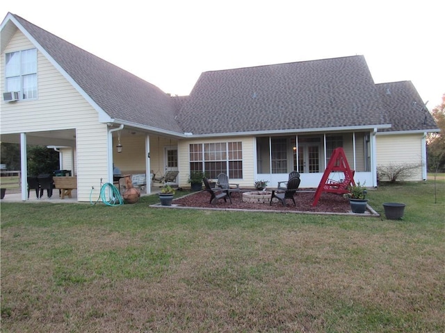 back of property featuring a sunroom, a lawn, cooling unit, an outdoor fire pit, and a patio