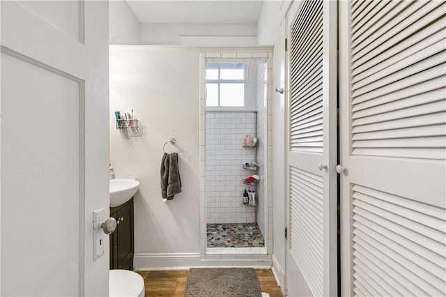 bathroom featuring tiled shower, hardwood / wood-style floors, vanity, and toilet