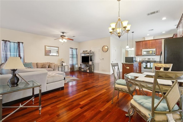 dining room with ceiling fan with notable chandelier and dark wood-type flooring