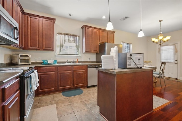 kitchen featuring decorative light fixtures, a center island, appliances with stainless steel finishes, and a chandelier