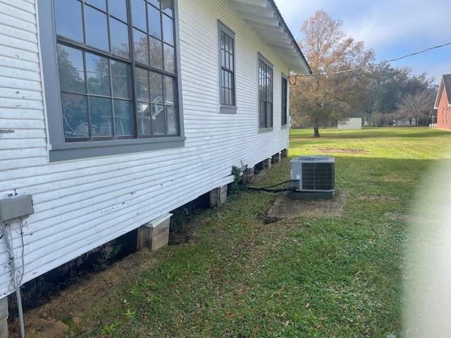 view of side of property with a yard and central air condition unit