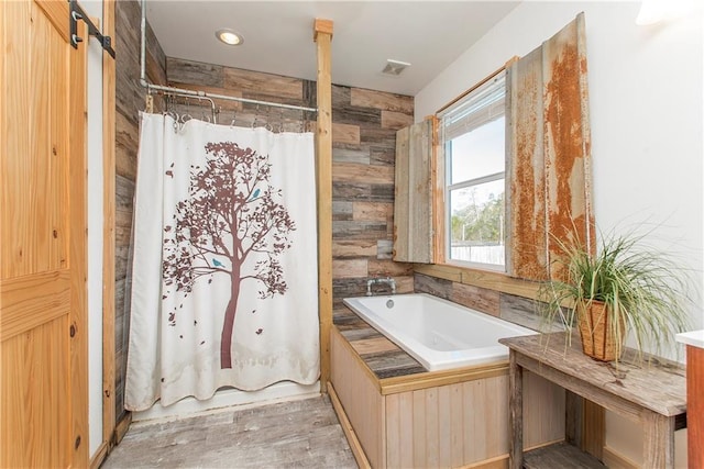 bathroom with a bath, wood-type flooring, and wooden walls