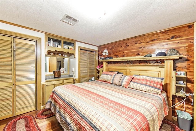 bedroom with wood-type flooring, a textured ceiling, and wooden walls