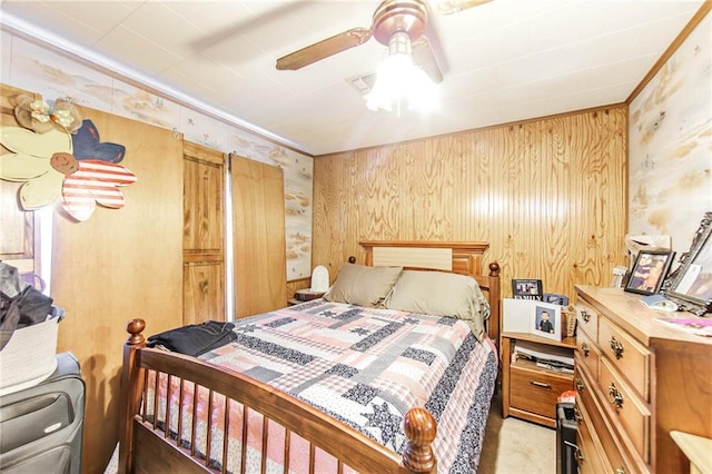 carpeted bedroom with ceiling fan and wood walls