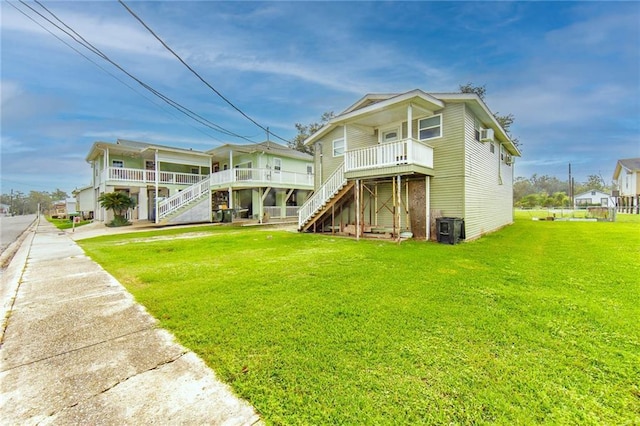 rear view of house with central AC unit, covered porch, and a yard